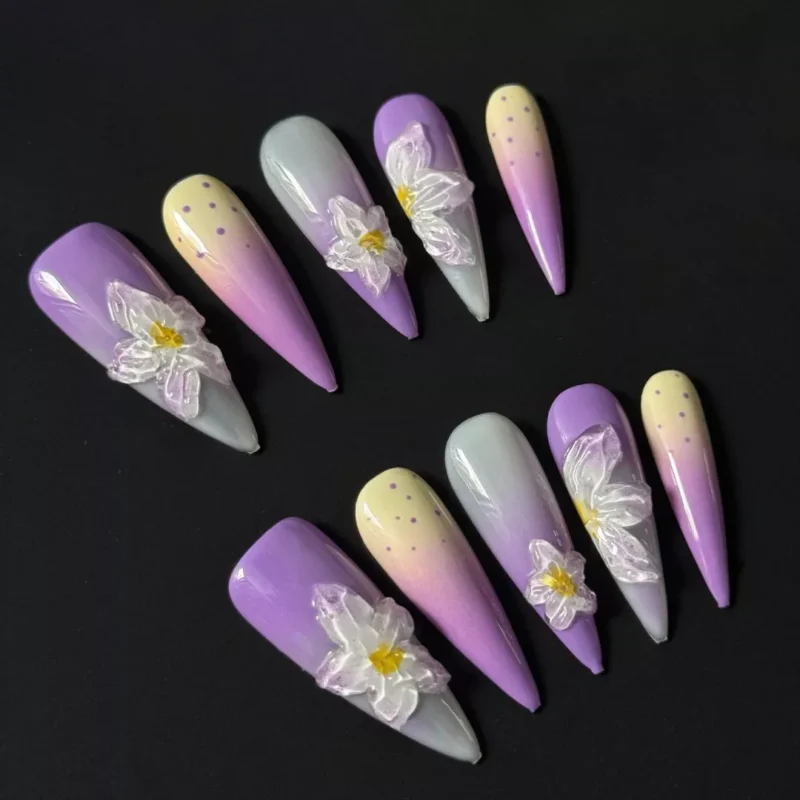 Purple ombre press-on nails with 3D white floral accents on black background