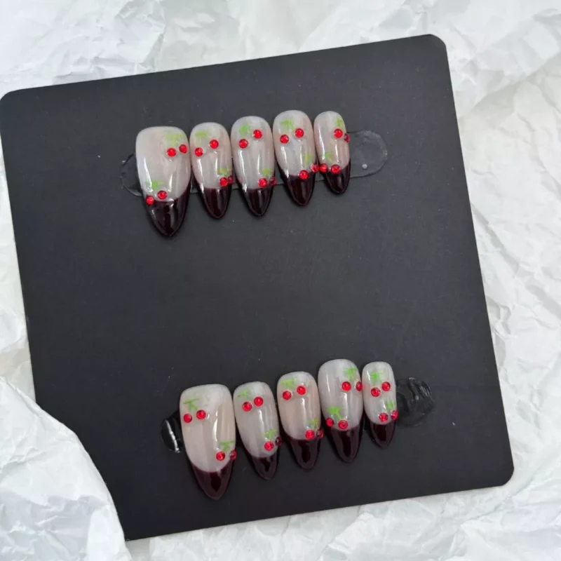 Full set of Rhinestone Cherry Press-On Nails on hand, showing nude and dark red contrast
