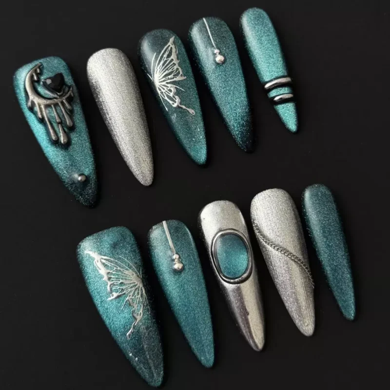 Side view of long square teal glitter nail with silver butterfly and chain details