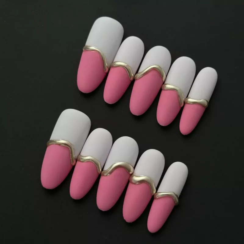 Side angle of pink matte dual-tone press-on nails with white and gold wave designs