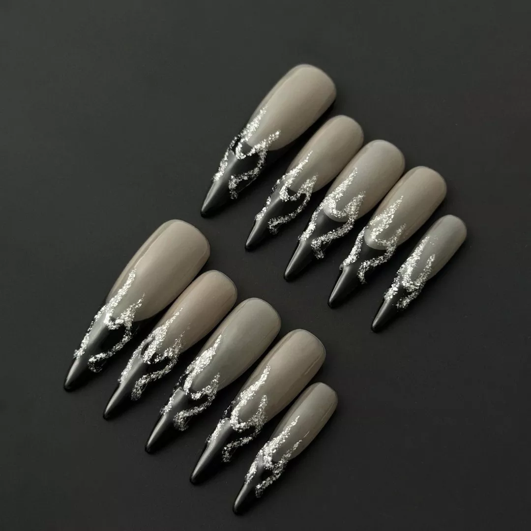Silver Flame Press-On Nails - Nude Base with Black French Edge 1 Silver flame press-on nails with nude base and stiletto shape – angled view