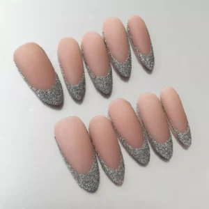 Close-up of silver French tip on matte nude almond press-on nail with textured glitter