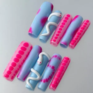 Close-up of stiletto nail with 3D white snake curve and pink dot pattern on gradient base