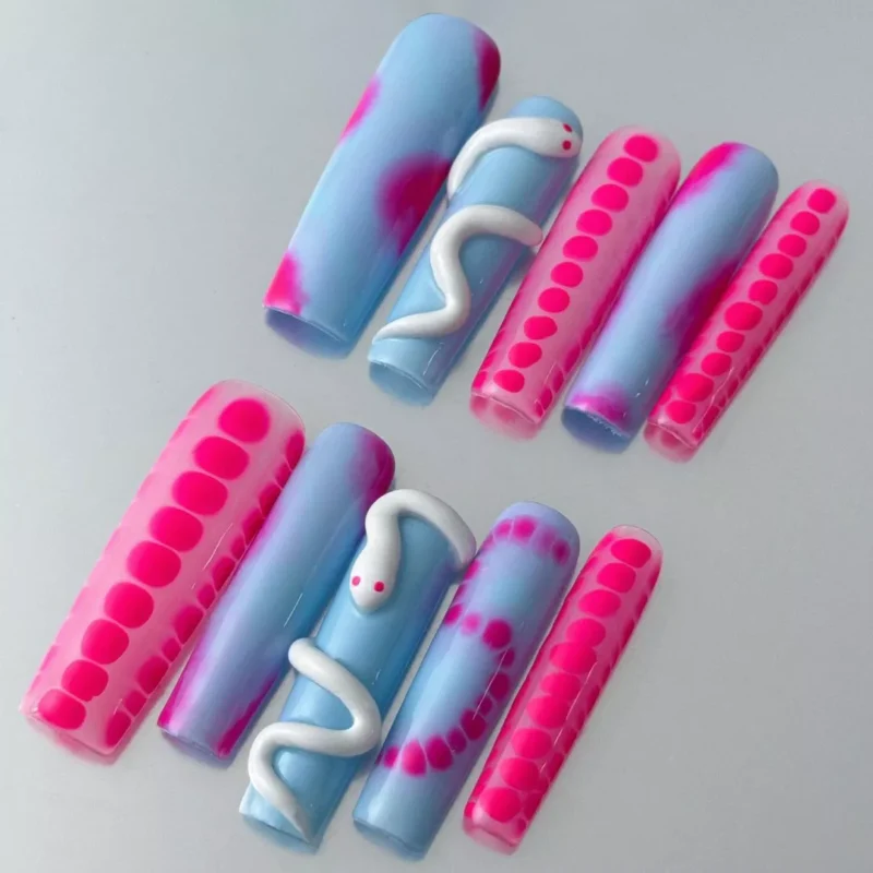Close-up of stiletto nail with 3D white snake curve and pink dot pattern on gradient base