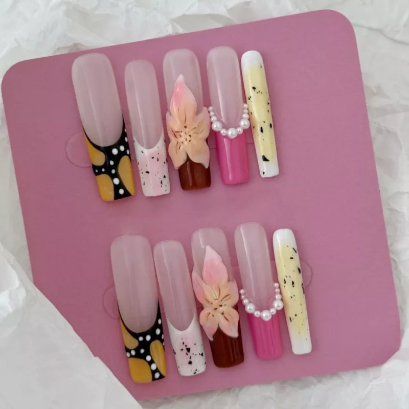 Speckled press-on nail tips with nude and pastel base and artistic detailing