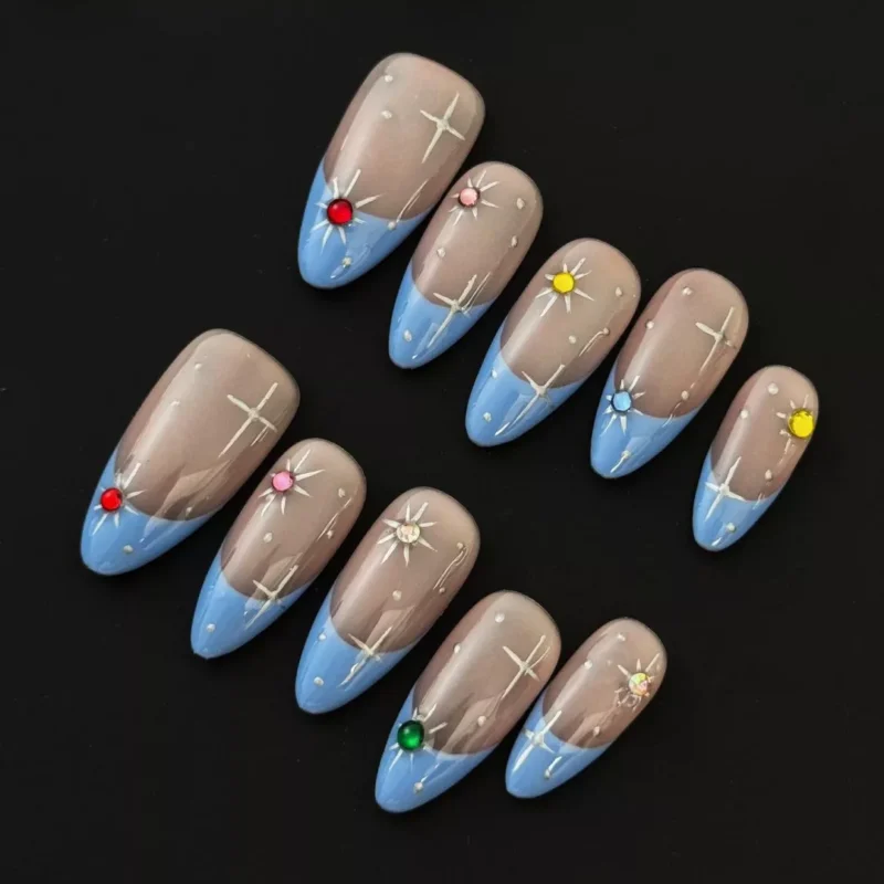 Sheer base starburst press-on nails with blue French tips and multicolor rhinestone accents – top view