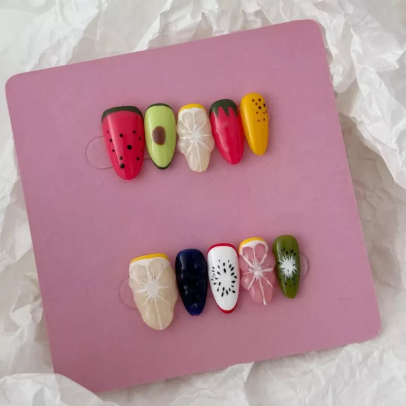 Styled display of 3D fruit nails including watermelon, strawberry, and citrus with glossy finish