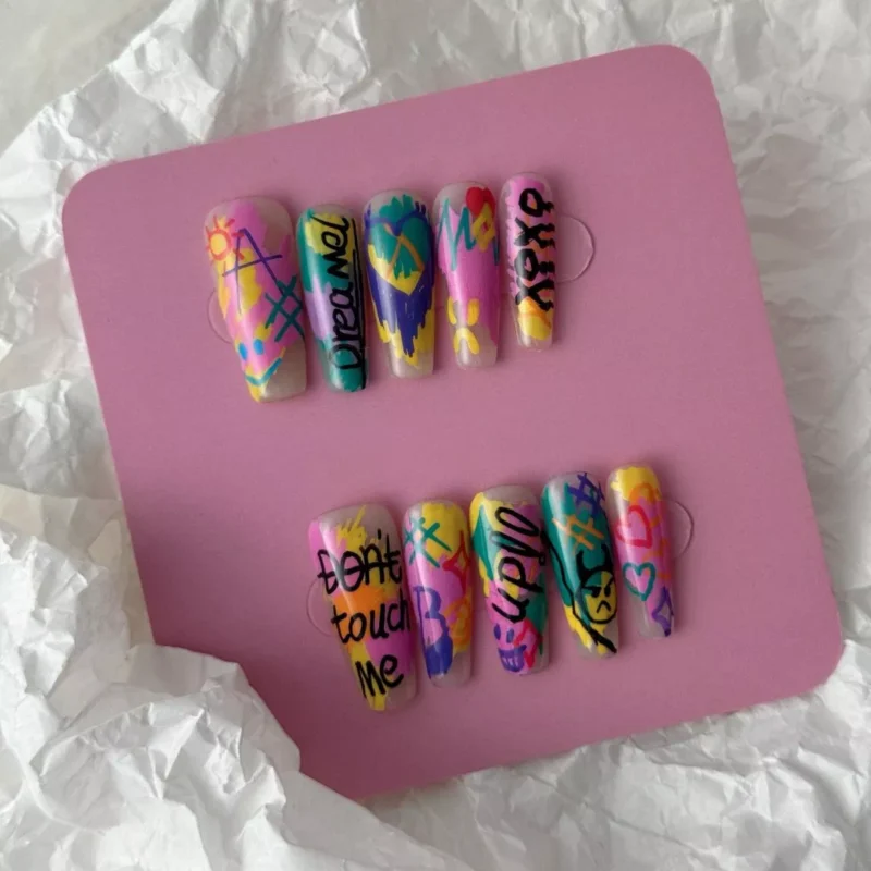 Urban tag-inspired nails featuring multicolor Y2K graffiti and abstract heart graphics