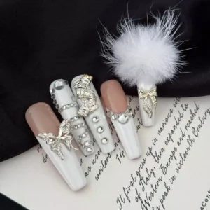 Long bridal press-on nails with nude base and luxury white accents, featuring soft pom detail