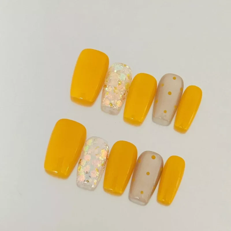 Close-up of Yellow Glitter Square Press-On Nails in soft daylight on white background