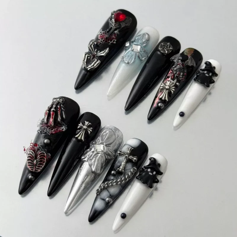 Black stiletto nails featuring 3D skeleton hand and silver cross charms on matte finish