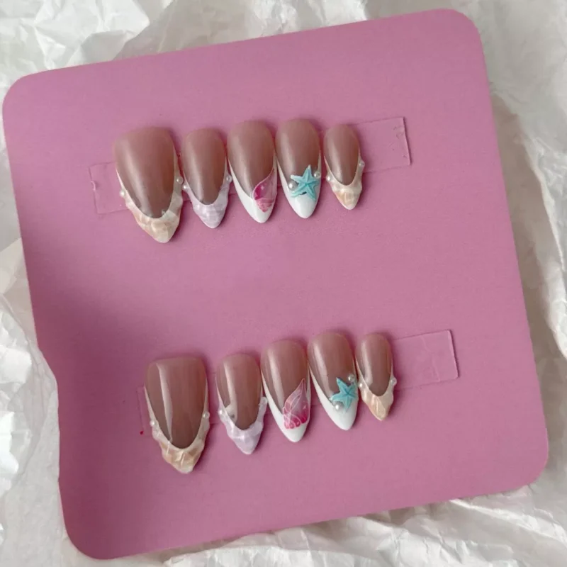 Artistic nude nails with sculptural seashell designs, pearls, and star embellishments
