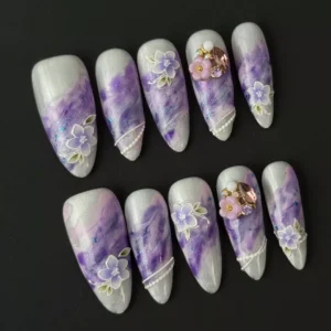 Medium almond purple nails with glossy marble texture and gemstone accents
