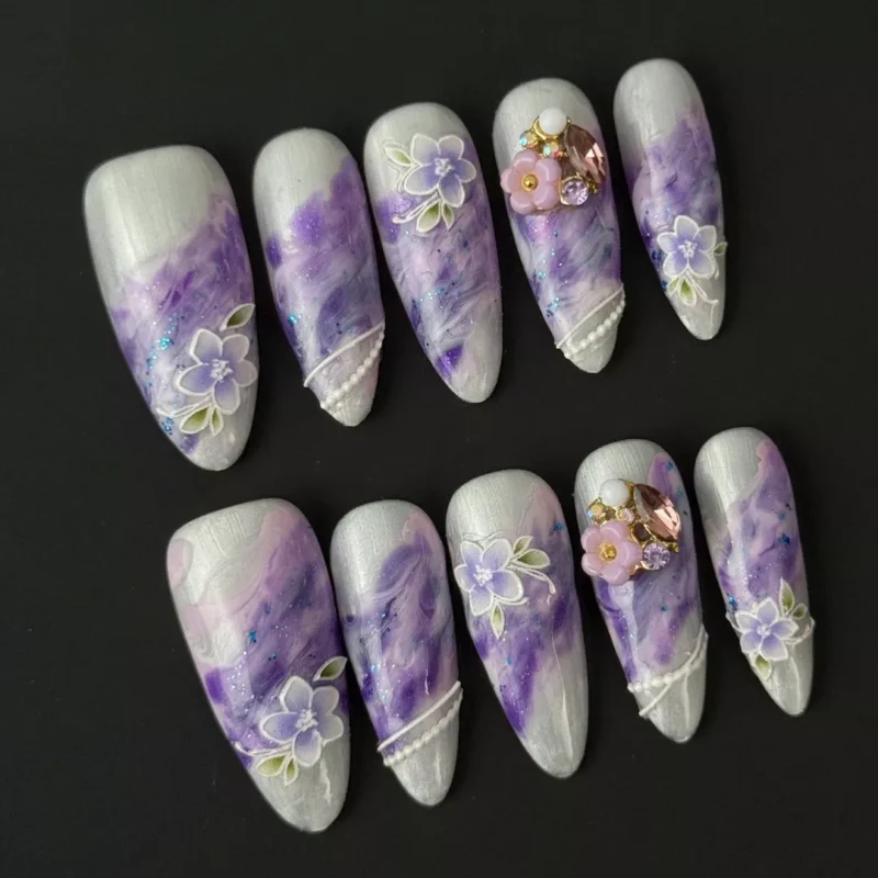 Medium almond purple nails with glossy marble texture and gemstone accents