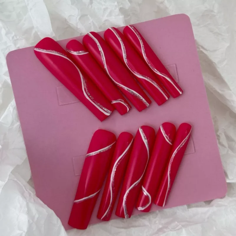 Magenta coffin fake nails with glossy finish and wave pattern – hand styling showcase