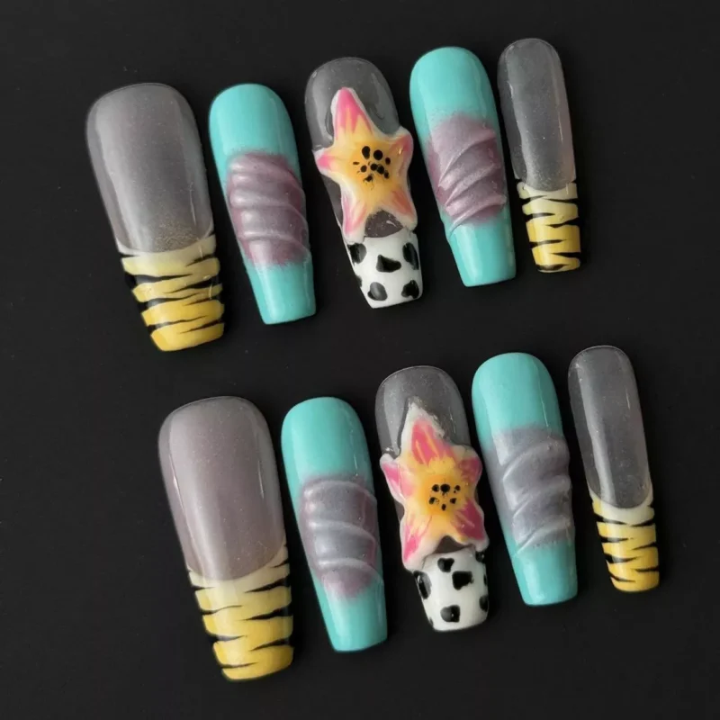 Close-up of cow print nail art on aqua and yellow base