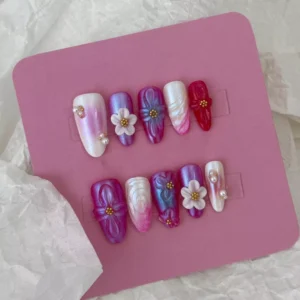 Medium almond nails with pearlescent floral nail art and gold center accents