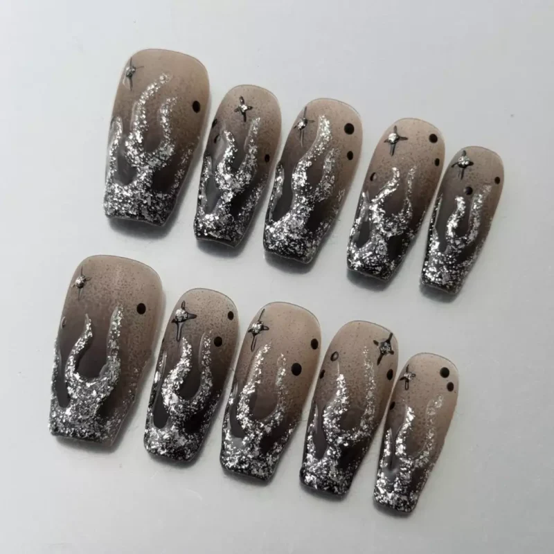 Side angle of ombre black and silver nails with star charms and glitter flame detailing