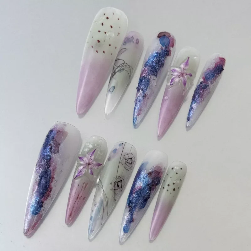 Close-up of glitter lily nail art on purple gradient press-on nails – long stiletto style