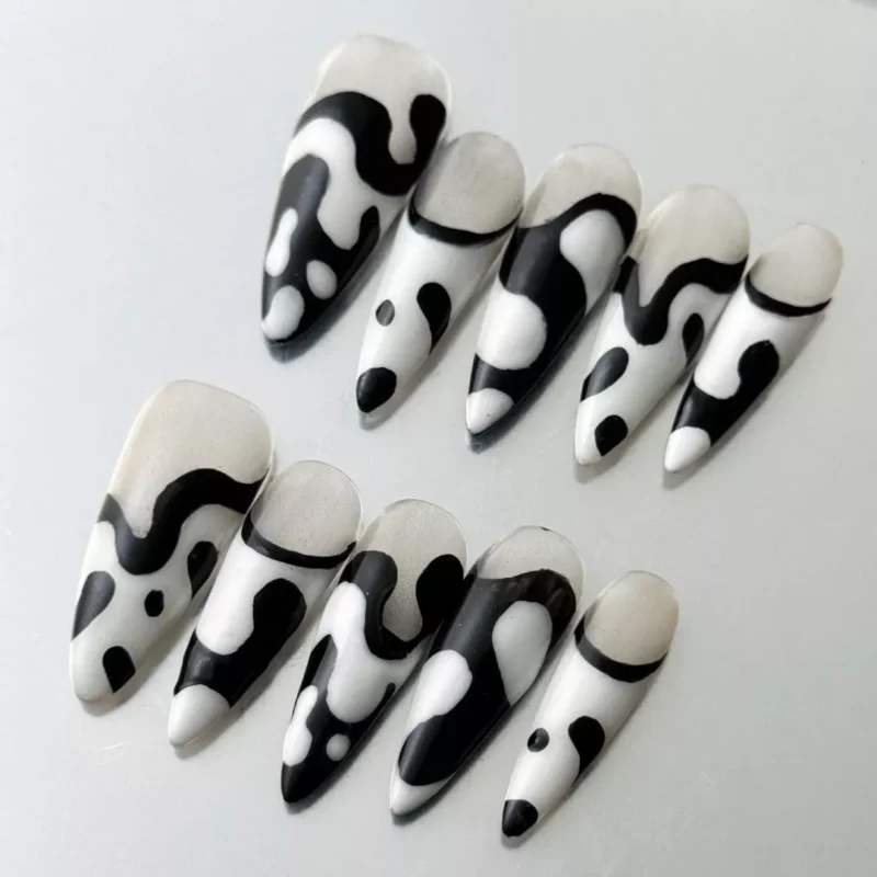 Glossy stiletto press-on nails in black and white with asymmetric abstract pattern