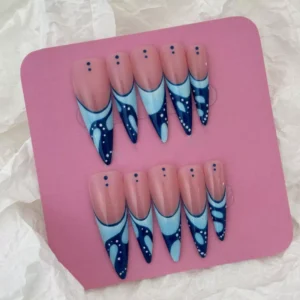 Long stiletto press-on nails in glossy nude and blue with dot accents – flat lay