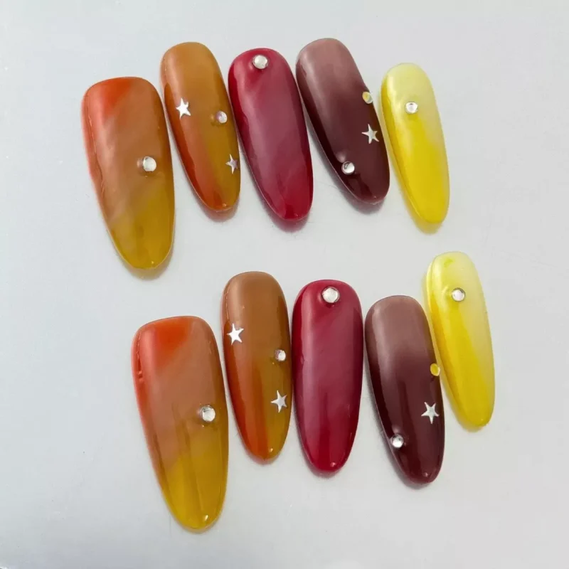 Glossy red and yellow gradient nails with rhinestone detail and coffin shape