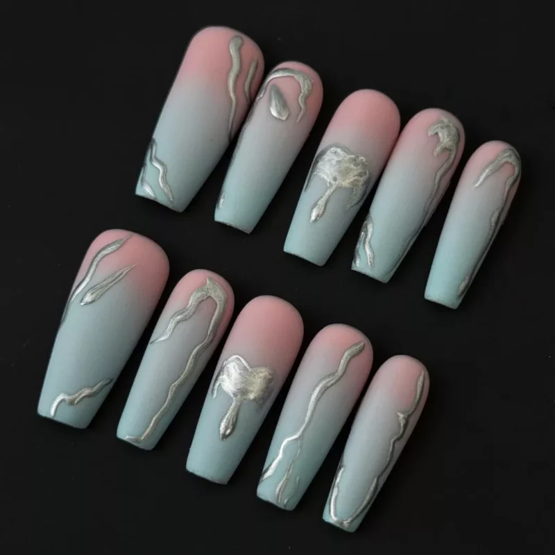 Gradient matte press-on nails with blush and teal ombre fade, featuring molten silver chrome lava design – front display