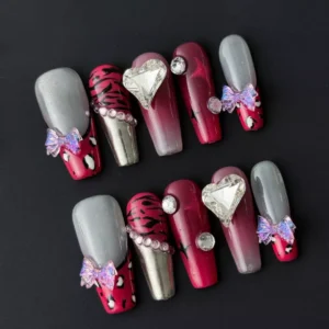Close-up of heart gem press-on nail with red chrome finish and animal print
