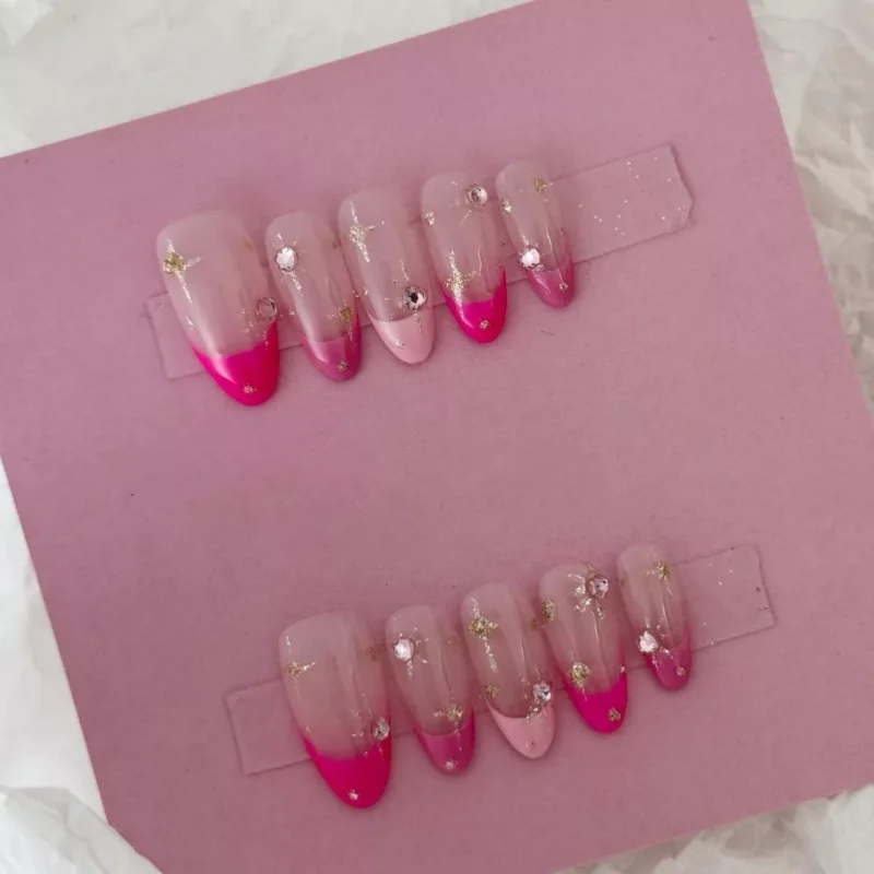 Sheer French nails with pink gradient tips, rhinestones, and glitter finish