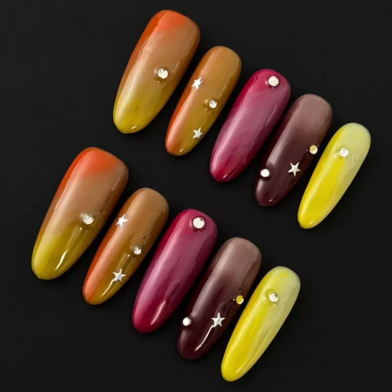 Multicolor warm tone press-on nails with glossy finish and star rhinestone accents – front angle view