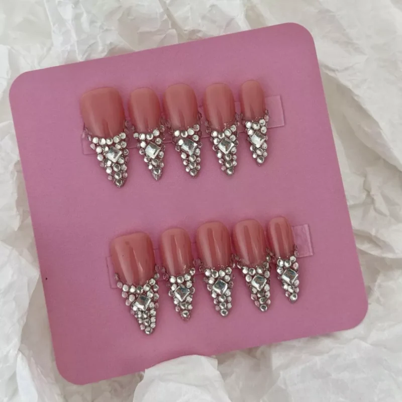 Almond shaped nude pink press-on nails with V-tip crystal accents – top view