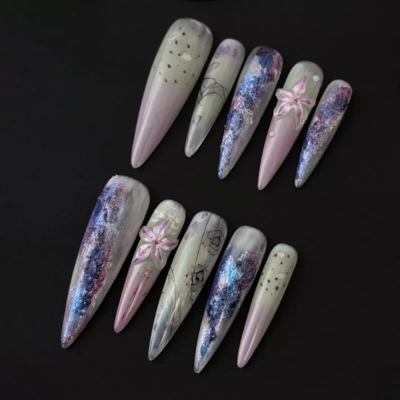 Purple glacier gradient press-on nails with glitter lily details and stiletto shape – front angle view