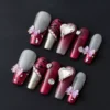 Red gradient chrome press-on nails with heart gem and leopard print accent – angled view