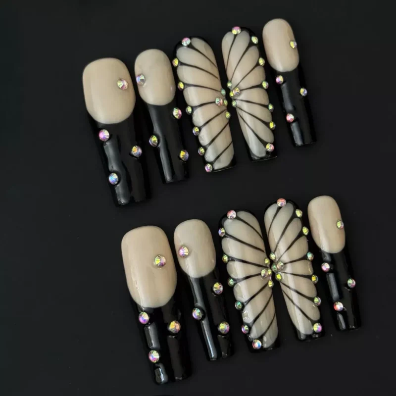 Detailed view of rhinestone butterfly accent nails on nude and black press-ons