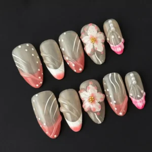 Side angle of pink tip almond nails with cherry blossom and gold accent detail
