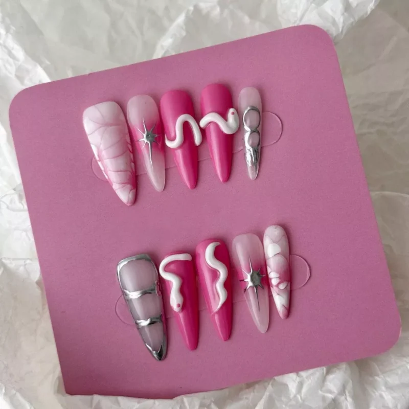 Pink marble press-on nails with metallic star and snake accents – angled view
