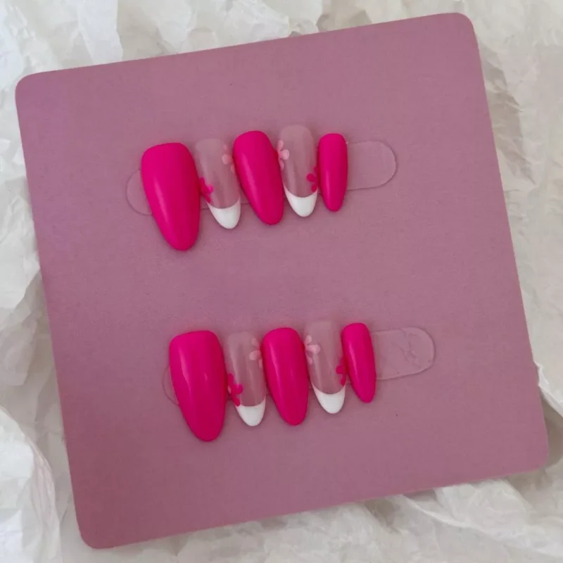 Sheer base pink press-on nails with flower details and bold V-tip contrast – nail art macro