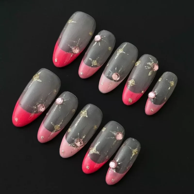 Sheer gold glitter French nails with pink rhinestone accents and star charms – front view