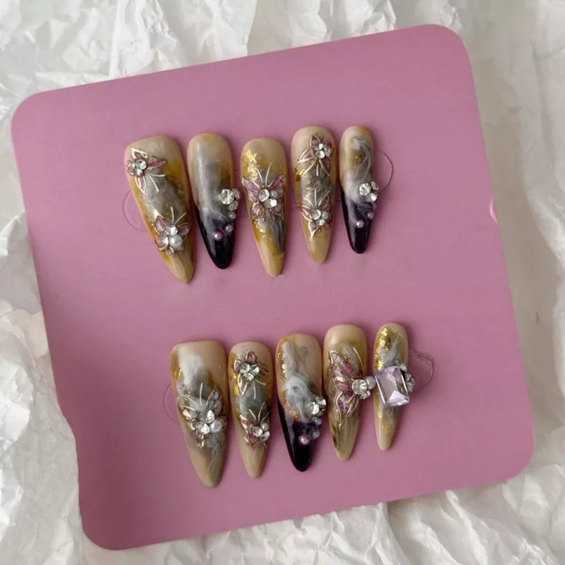 Set of smoky marble press-on nails in medium oval shape with sculpted florals and gem accents