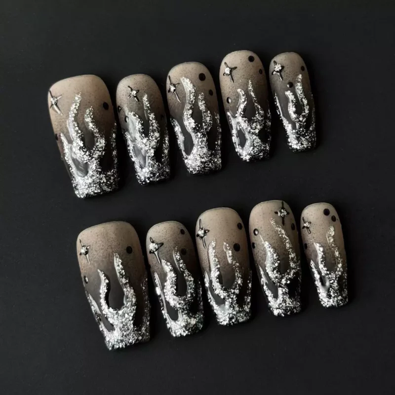 Close-up on square nail tips featuring star charm ombre design in black and silver