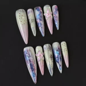 Side angle of long stiletto press-on nails in purple icy tones with embedded lily accents
