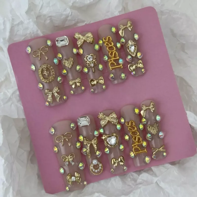 Hand model wearing nude coffin press-on nails with astrology charms and glossy finish