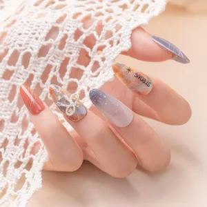 Hand featuring glittery bow nail charm applied over orange-purple nail design