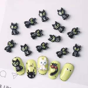 Black cartoon cat nail charms with bright green eyes and glossy surface shown with nail tip samples
