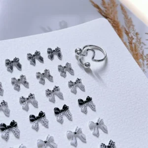 Collection of black and white 3D bow nail embellishments under natural lighting