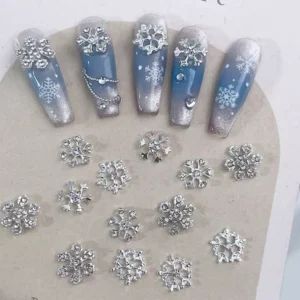 3D Snowflake Nail Art charms in gold and silver laid out with demo nails