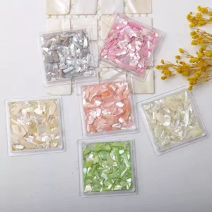 Assorted abalone shell nail flakes in pastel tones including pink, green, and silver