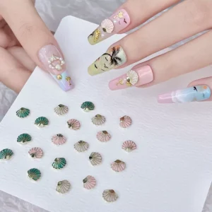 Close-up of pastel green, pink, and ivory Alloy Seashell Nail Charms styled on coastal beach theme manicure