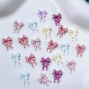 Assorted pastel bow nail charms arranged on a white ceramic plate