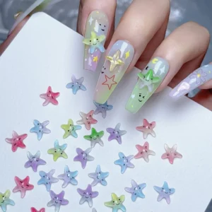 Hand showing pastel nail art decorated with Aurora Resin Nail Charms in starfish, star, and letter shapes